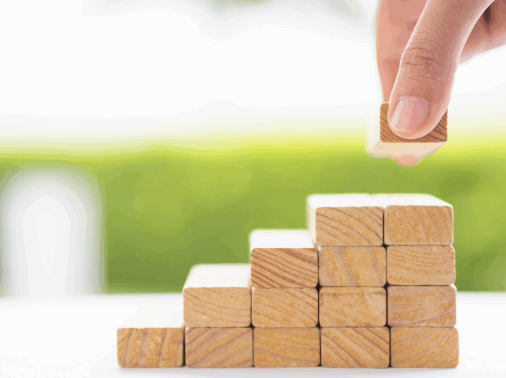 A hand is putting a block on the top of a stack of blocks