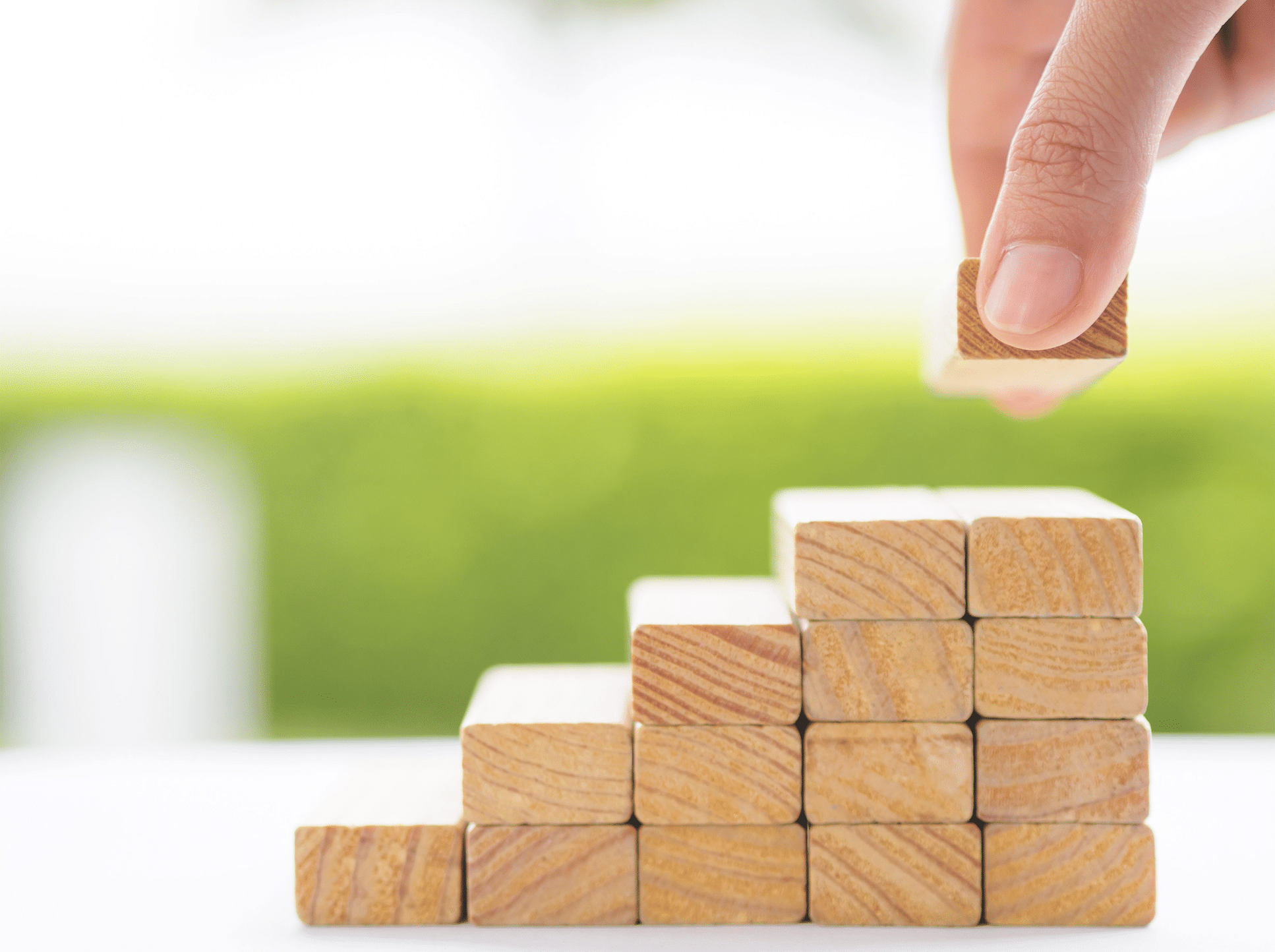 A hand is putting a block on the top of a stack of blocks